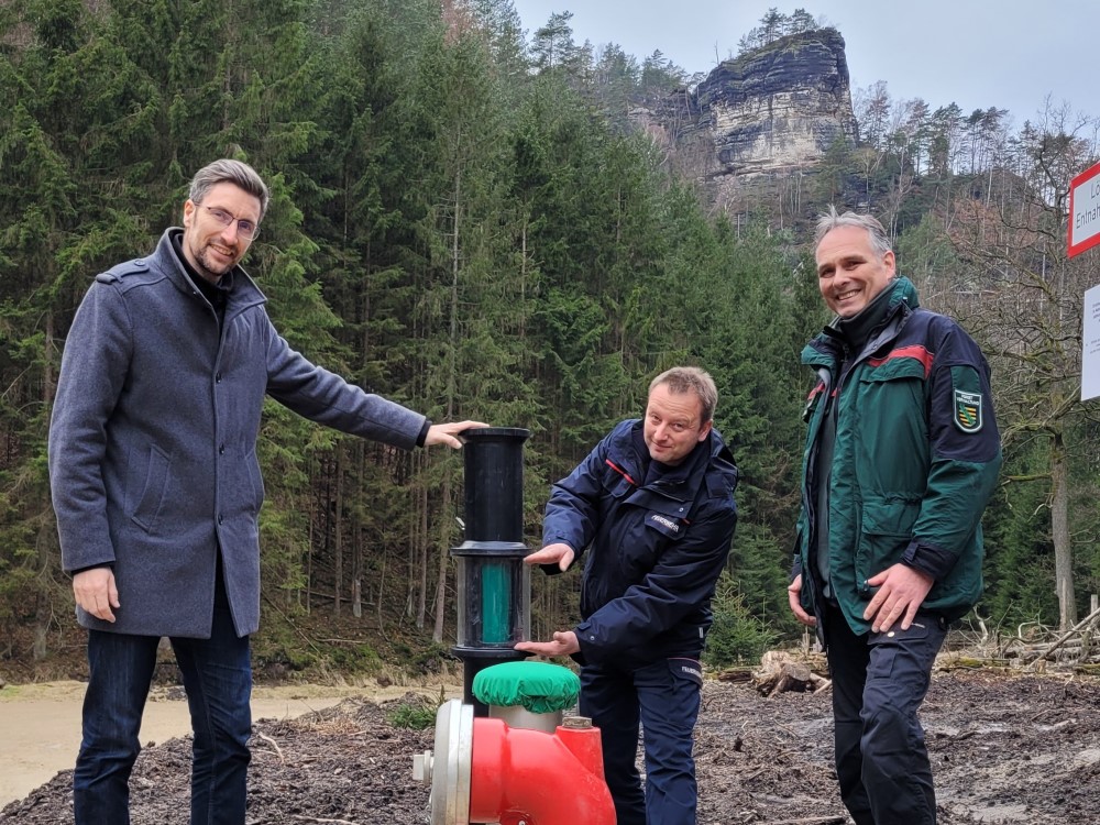 Foto: © Hp. Mayr  - Die Stadverwaltung Sebnitz hat mit Hilfe von Fördermitteln des Umweltministeriums im vergangenen Jahr drei Löschwasserzisternen im Nationalpark bauen lassen. Nun konnten der Sebnitzer Oberbürgermeister Ronald Kretzschmar, Stadtwehrleiter und Gerätewart der Feuerwehr Björn Hoyer die Zisternen mit dem Leiter der Nationalpark- und Forstverwaltung Sächsische Schweiz vom Sachsenforst Uwe Borrmeister in Betrieb nehmen. Die Zisterne im Großen Zschand fasst 50.000 Liter. Ihr Füllstand lässt sich leicht im grünen Sichtfenster kontrollieren.