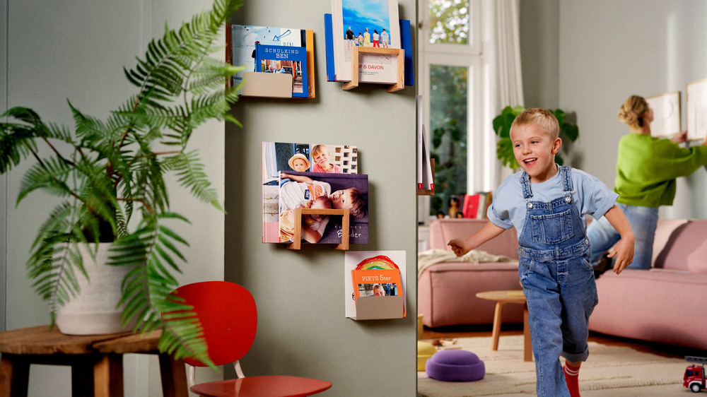 In kleinen Wandregalen werden Fotobücher selbst zum bunten Wandschmuck. Foto: DJD/CEWE