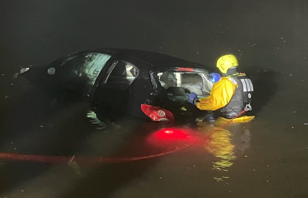 © Feuerwehr Dresden Ein Einsatzschwimmer bringt eine Rundschlinge am Fahrzeug an, damit es im Anschluss aus dem Wasser gezogen werden kann